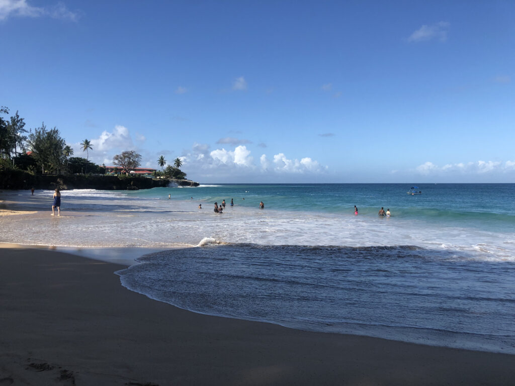 A photo of a beach with blue water and people swimming in the distance.